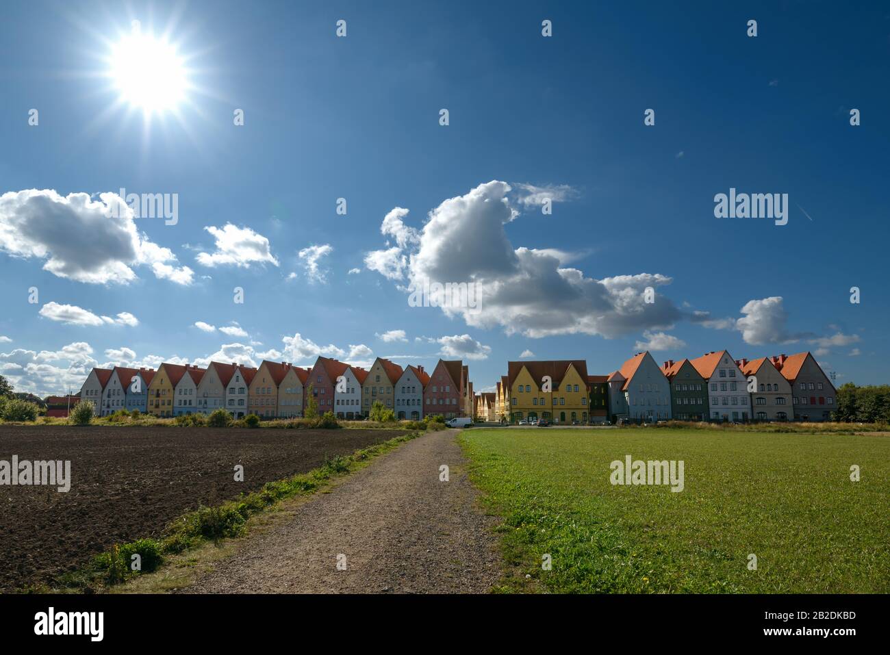 Field view of colorful houses with blue sky and sun in the