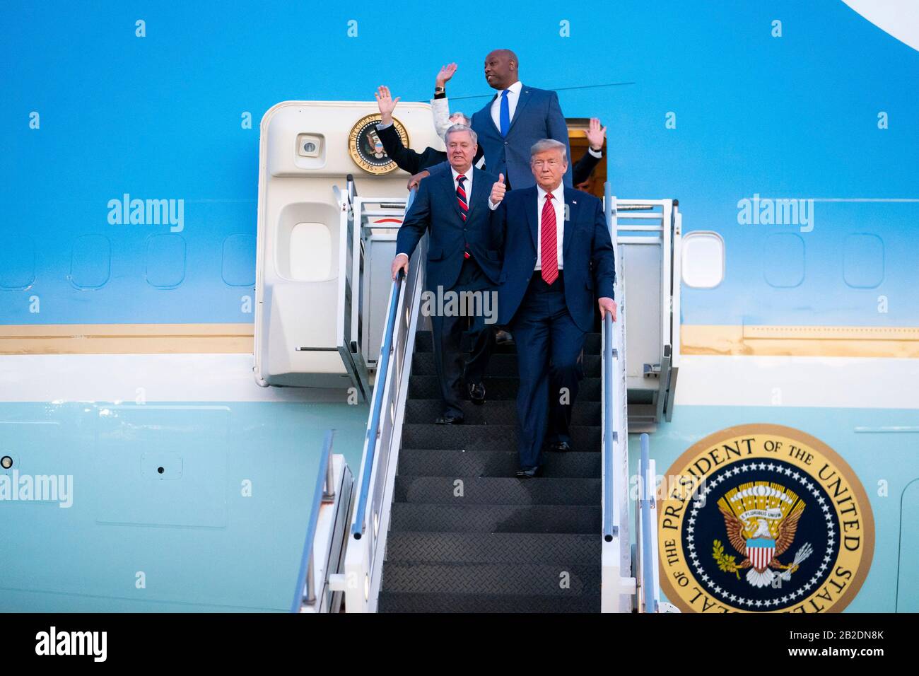 U.S President Donald Trump waves to supporters as he disembarks Air Force One accompanied by Senators Lindsey Graham and Tim Scott at Charleston International Airport February 28, 2020 in Charleston, S.C. Trump arrived Charleston to hold a campaign rally on the eve of the Democratic primary in the state. Stock Photo