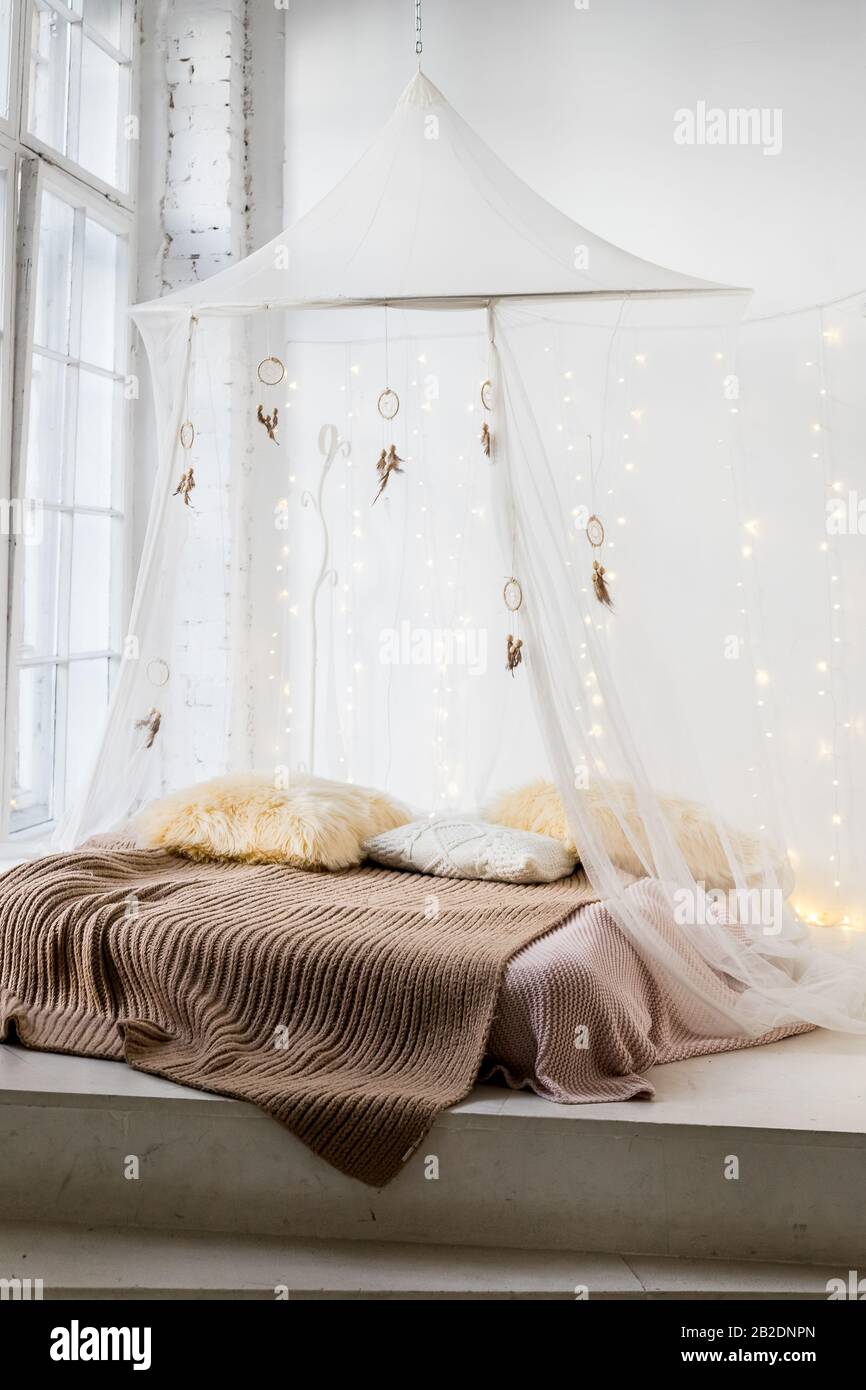 bed with patterned bedding and white drapes in bright bedroom interior.Cozy  scandinavian bedroom interior at mansard cabin. Boho style, merino woolen  Stock Photo - Alamy