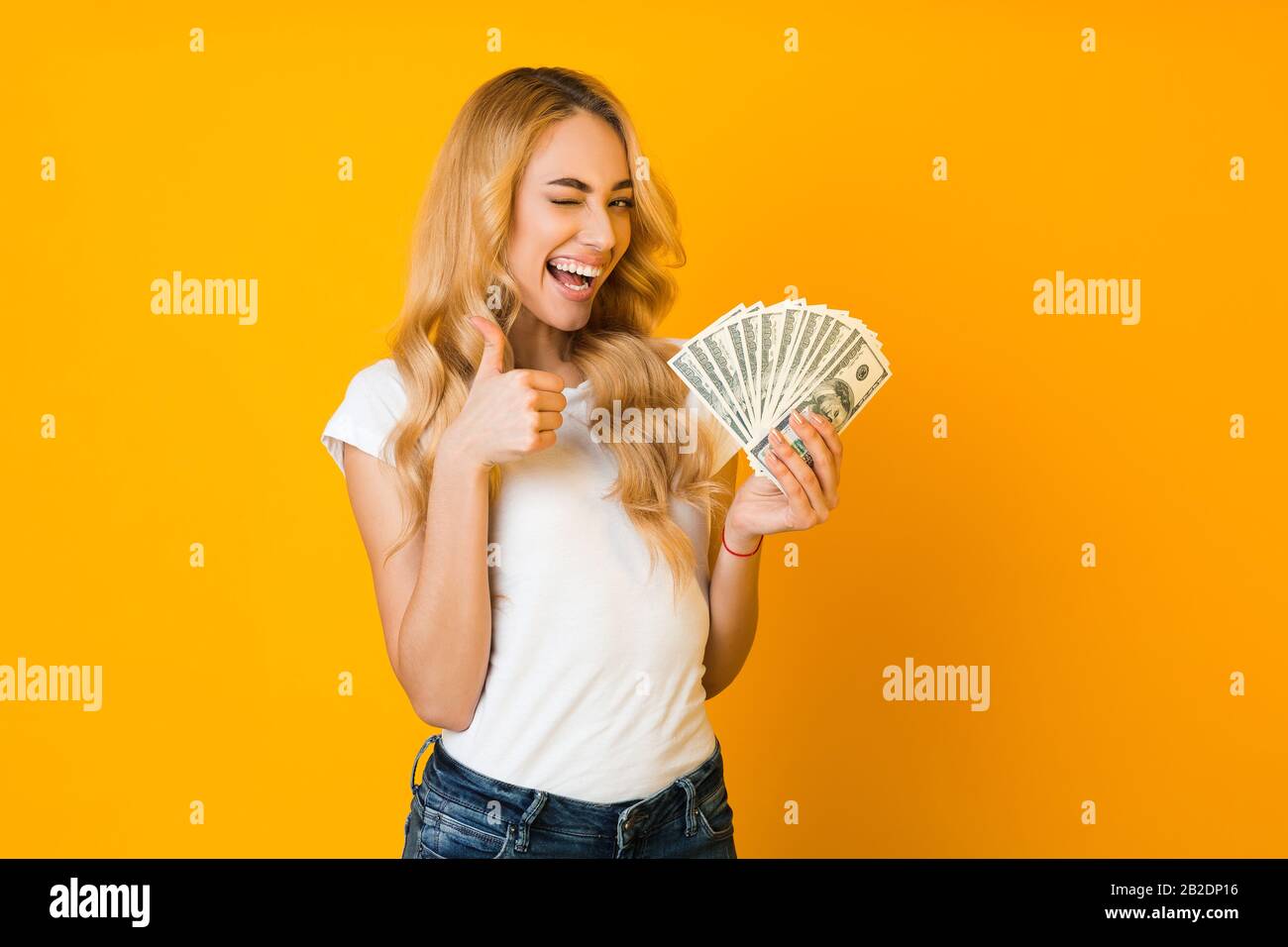 Cashback. Excited woman holding money banknotes and showing thumb up Stock Photo