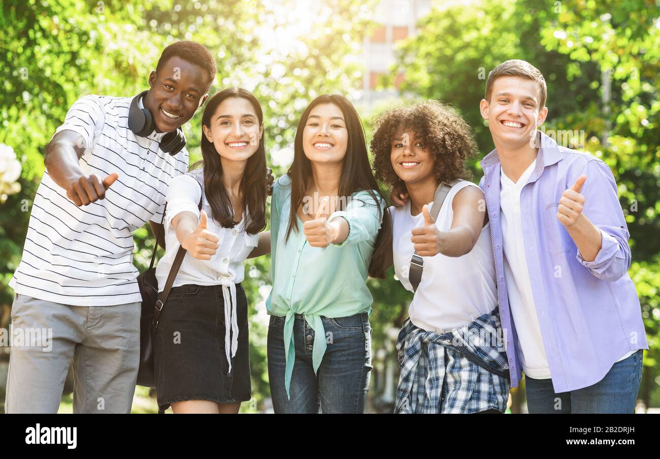 Happy Multicultural Teens Posing Together Outdoors And Showing Thumb Up Stock Photo