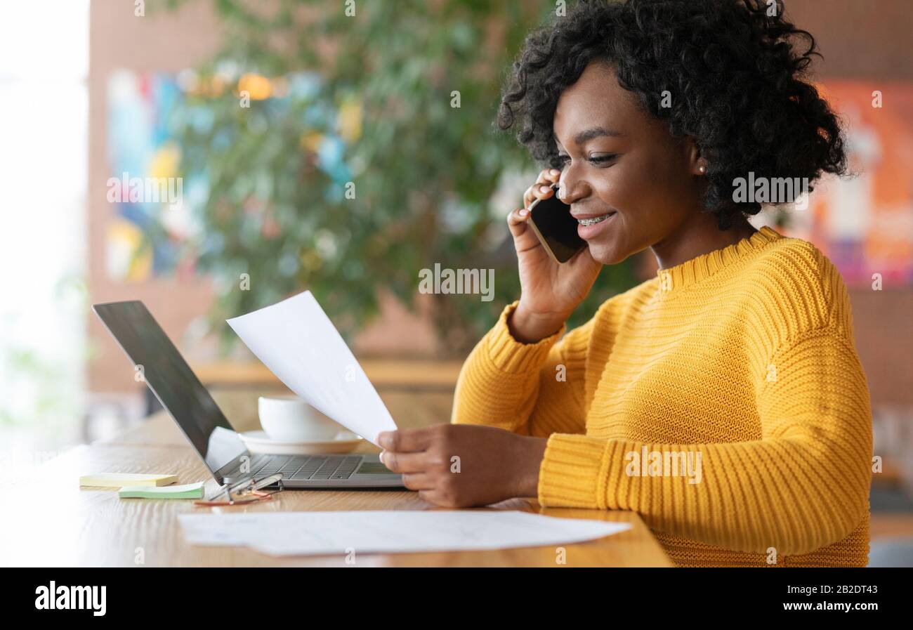 Young black girl editor talking to clients on phone Stock Photo