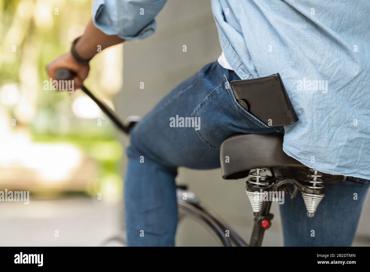 Wallet Falling Down From Pocket Of Unrecognizable Afro Guy On Bike Stock Photo