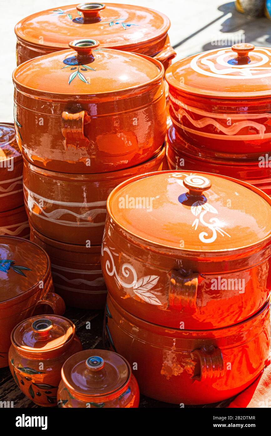 Handmade colorful ceramic cups, plates, pots, and cooking ware on sale