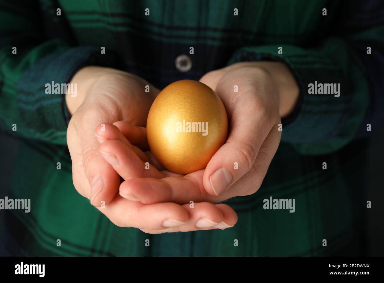 Woman in shirt holds golden egg, close up Stock Photo
