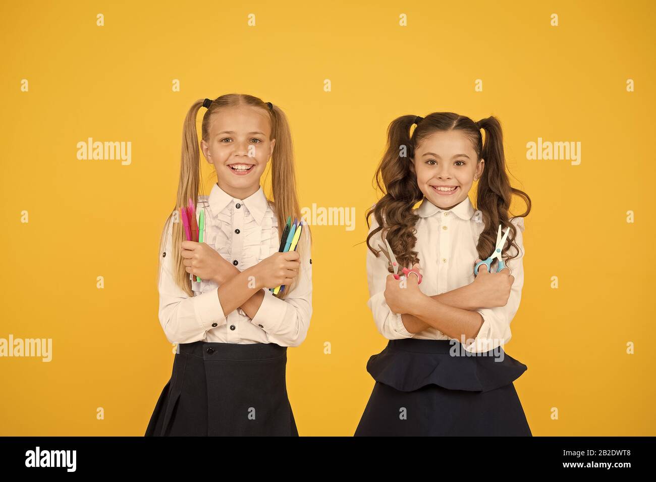 Inspire your children to get creative. Happy children holding scissors and markers. Little children smiling with handy tools on yellow background. Arts and crafts activities for small children. Stock Photo