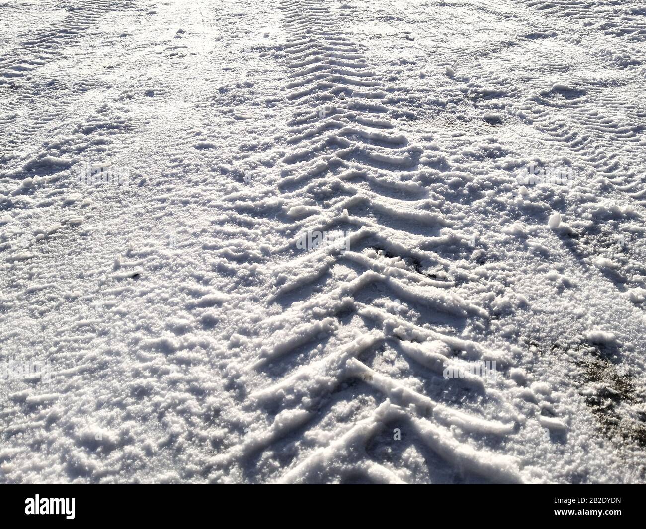 Traces of car tires in the snow in the light of the bright sun Stock Photo