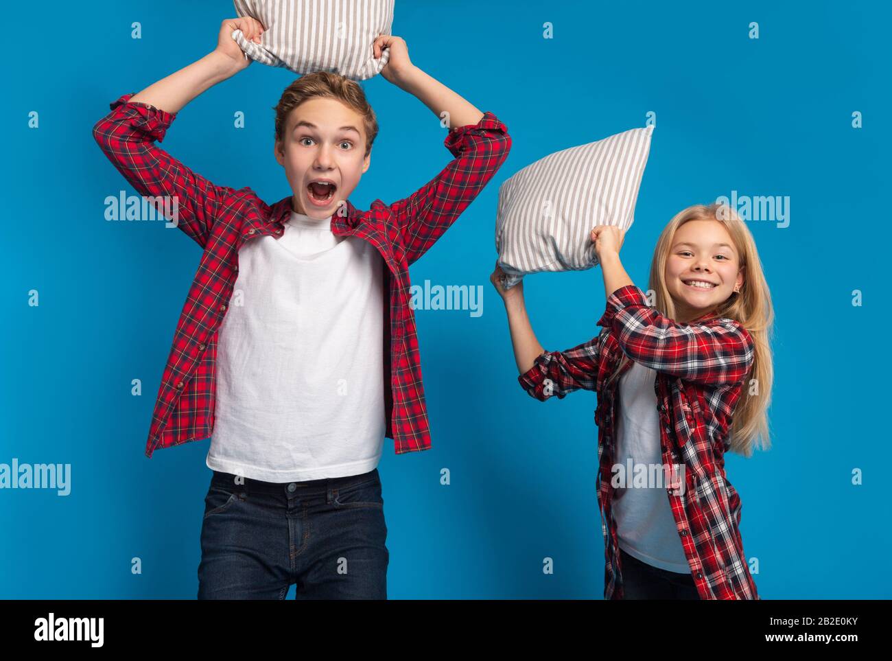 Playful Little Boy And Girl Fighting With Pillows At Camera Stock Photo