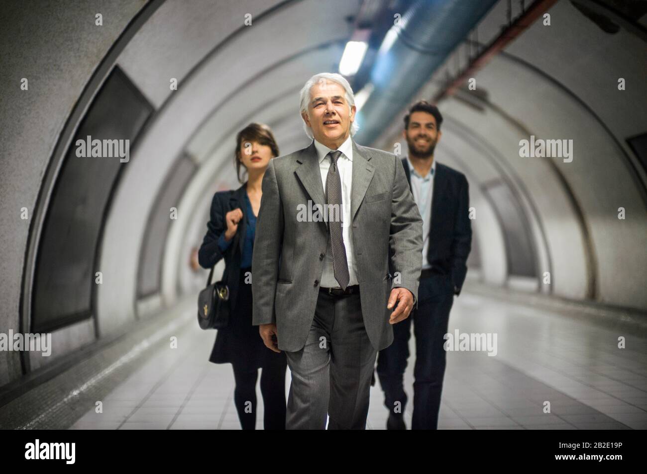 Three smiling business colleagues walking confidently in a subway tunnel Stock Photo