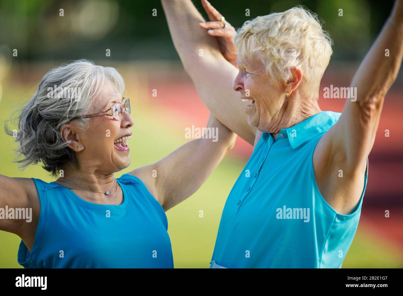 Two elderly friends celebrate crossing the finish line at an athletics event Stock Photo