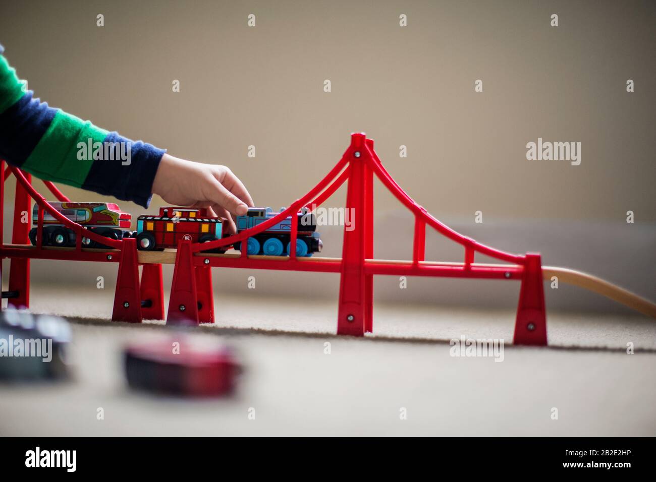Child playing with a toy train and bridge set Stock Photo