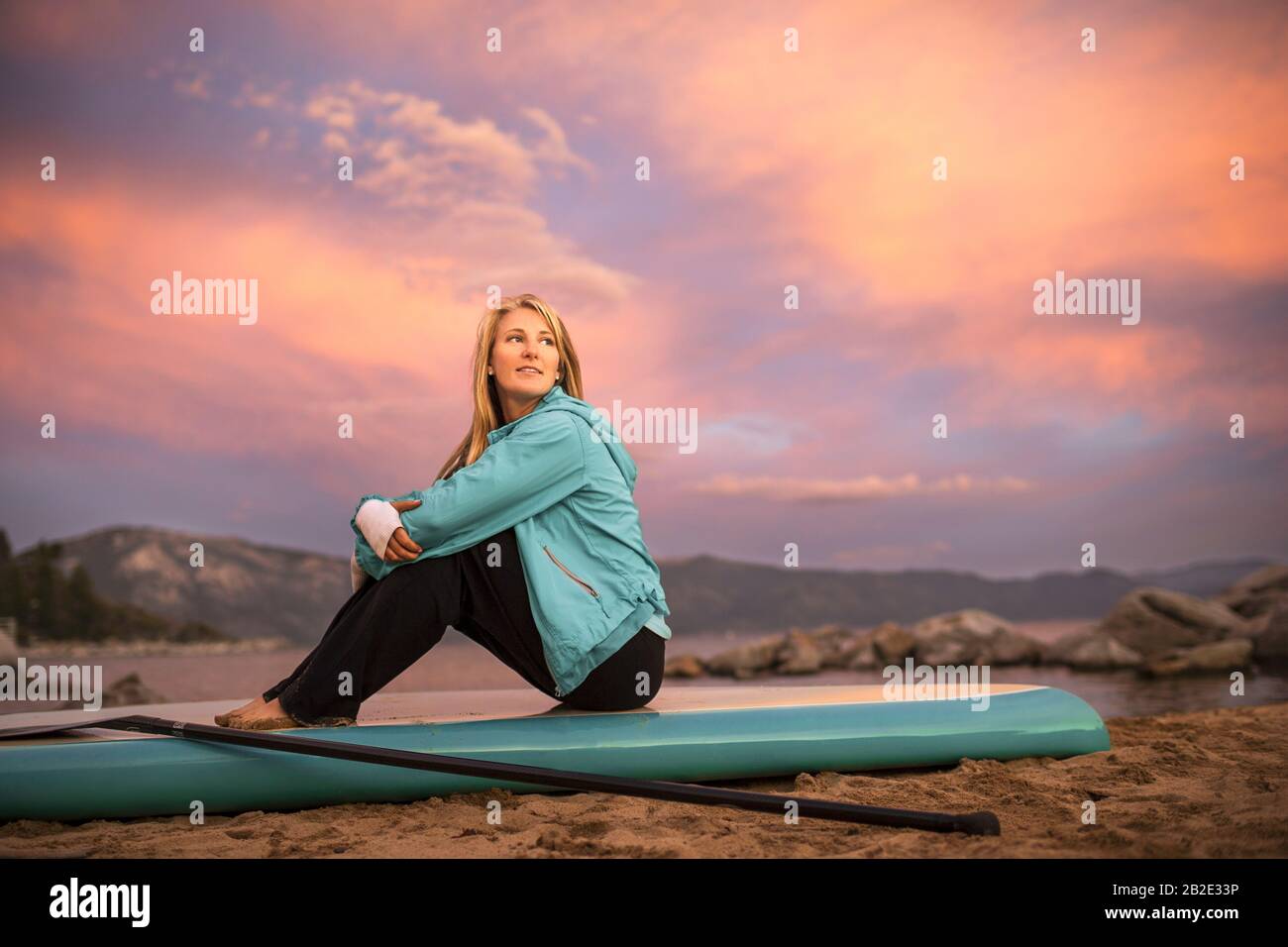 Young woman sitting on her paddle board at the beach Stock Photo