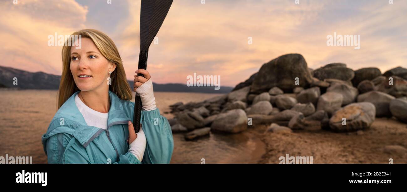 Mid adult woman standing by a lake holding a paddle Stock Photo