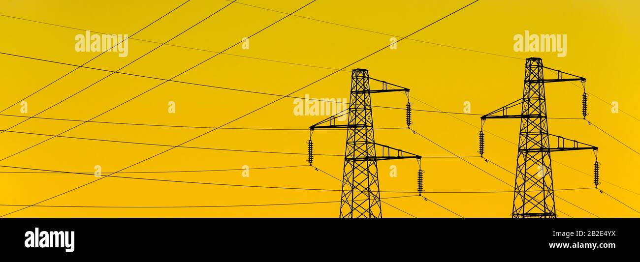 Electric power industry. Transmission towers or electricity pylons with golden sky background Stock Photo