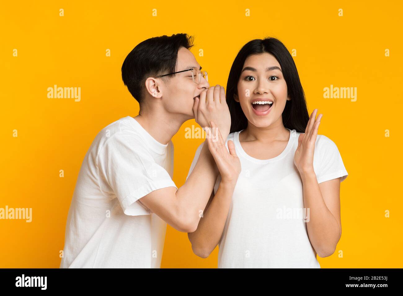 Asian man sharing secret with his emotional girlfriend Stock Photo - Alamy