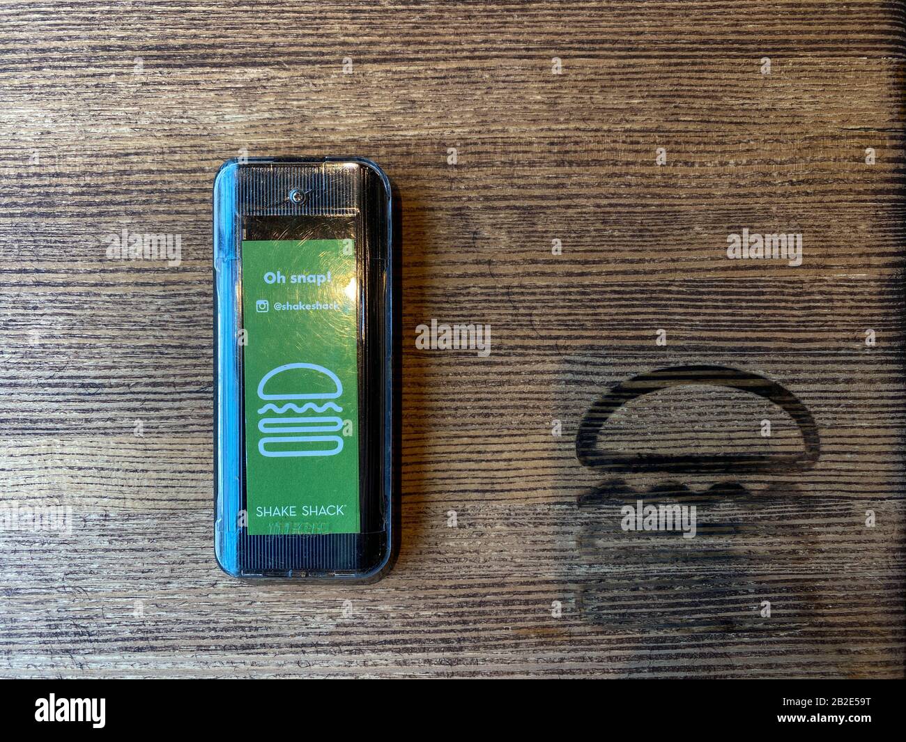 Orlando, FL/USA-1/22/20:  A pager on a wooden table at a Shake Shack restaurant.  Shake Shack is an American fast casual restaurant chain based in New Stock Photo