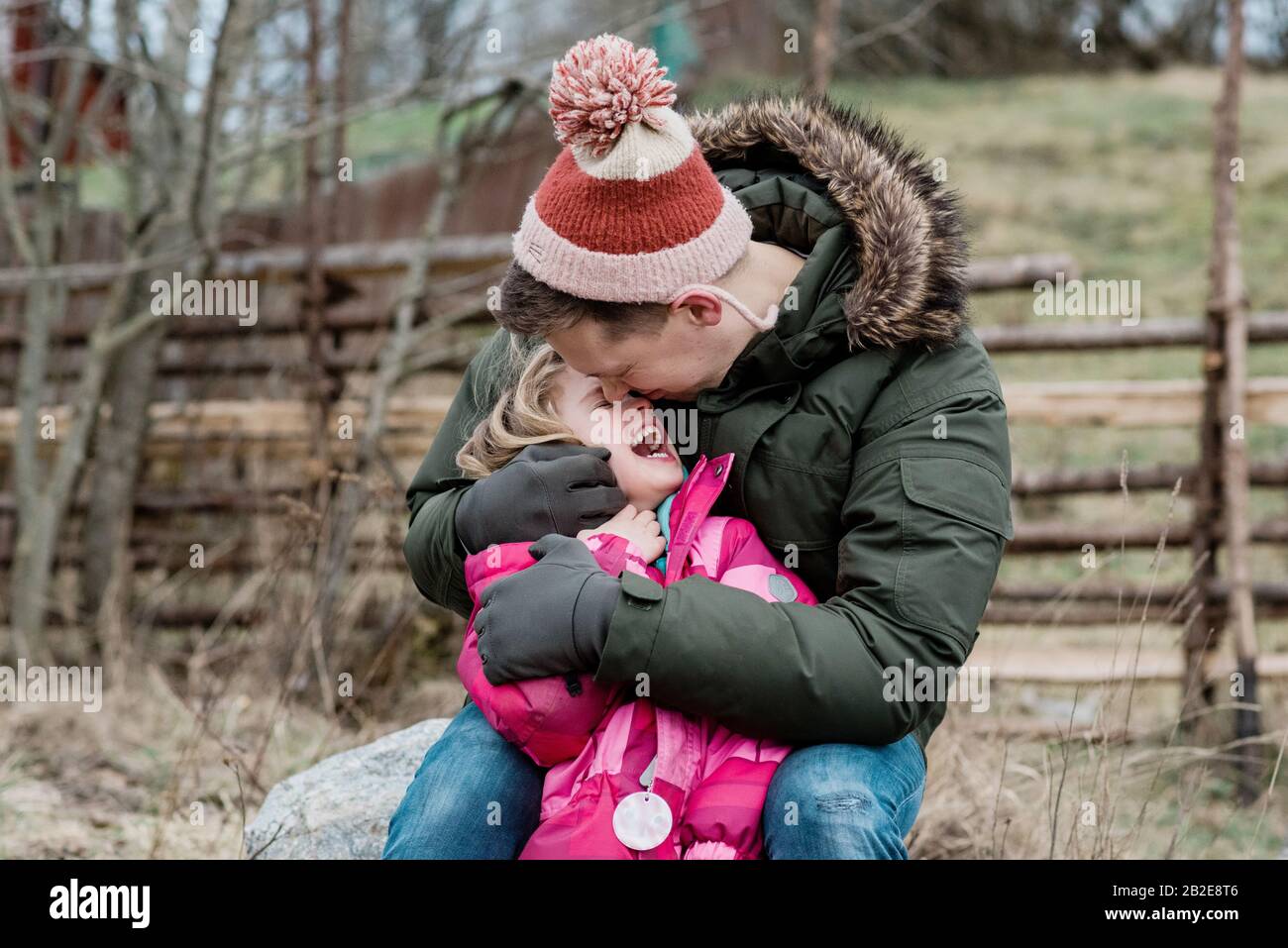 candid portrait of playful dad kissing his daughter outside Stock Photo