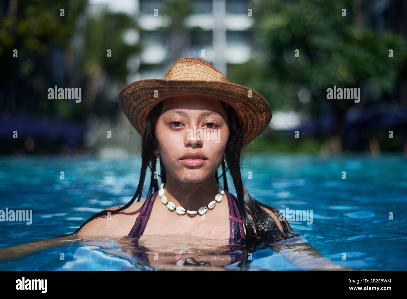 Stylish trendy young teen visco girl in the pool wearing a straw hat