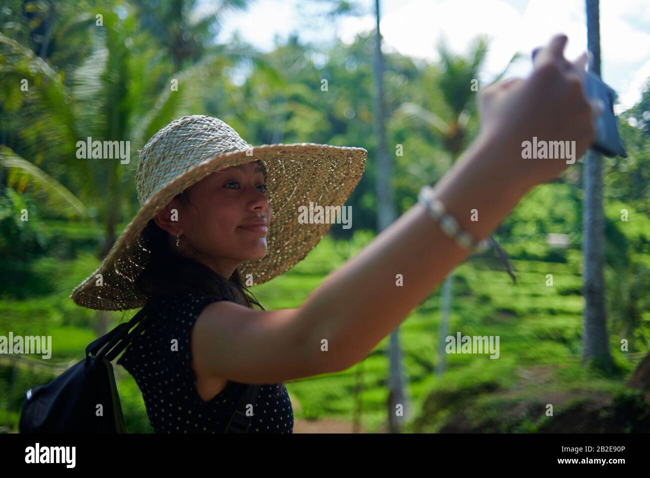 Teen girl wearing a big straw hat taking selfies using mobile phone Stock Photo