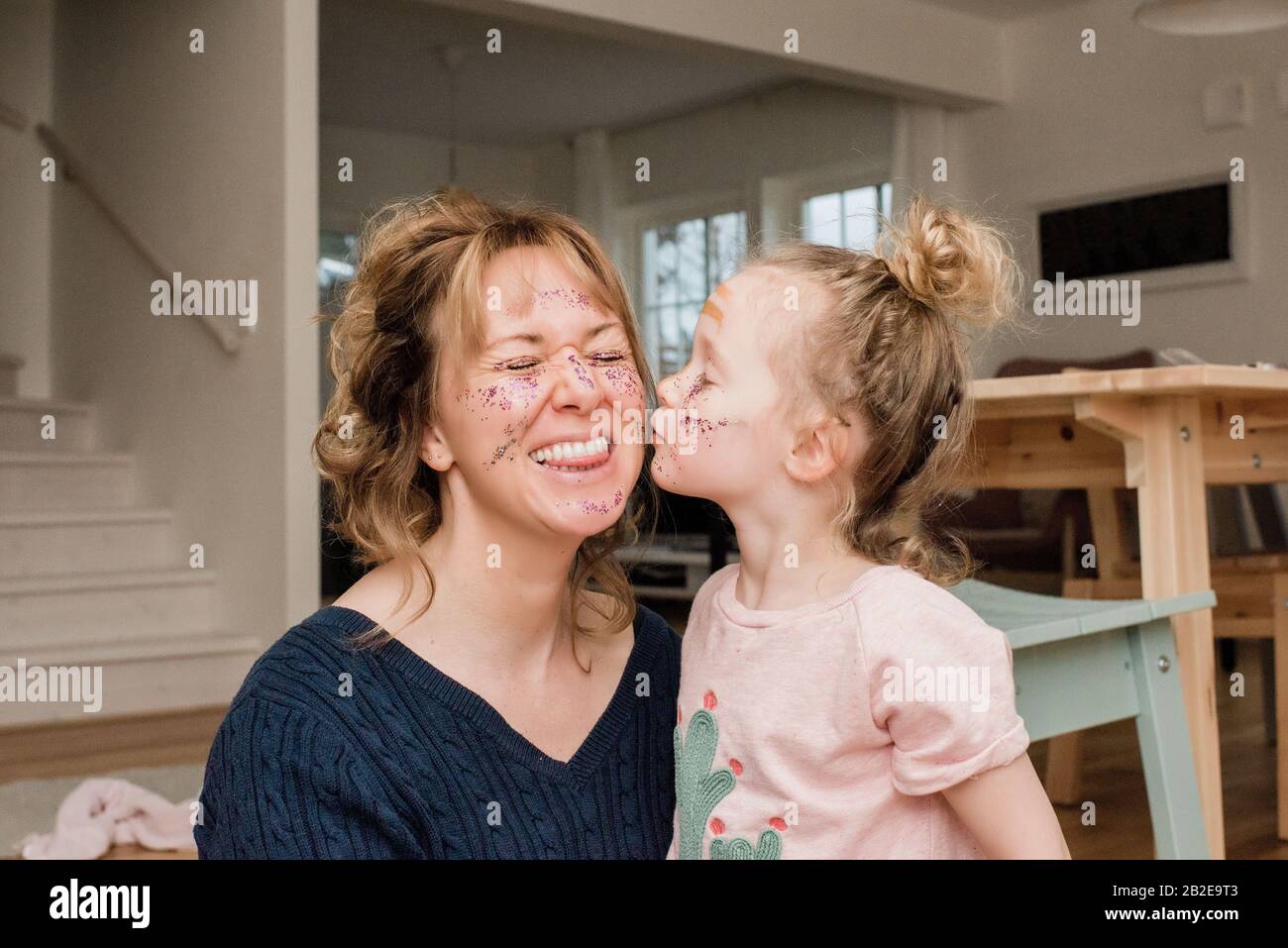 mother and daughter playing with make up at home laughing together Stock Photo