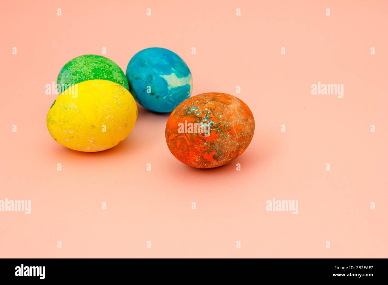 Four multi-colored Easter eggs on pink background top view, space for text. Concept happy easter day. Stock Photo