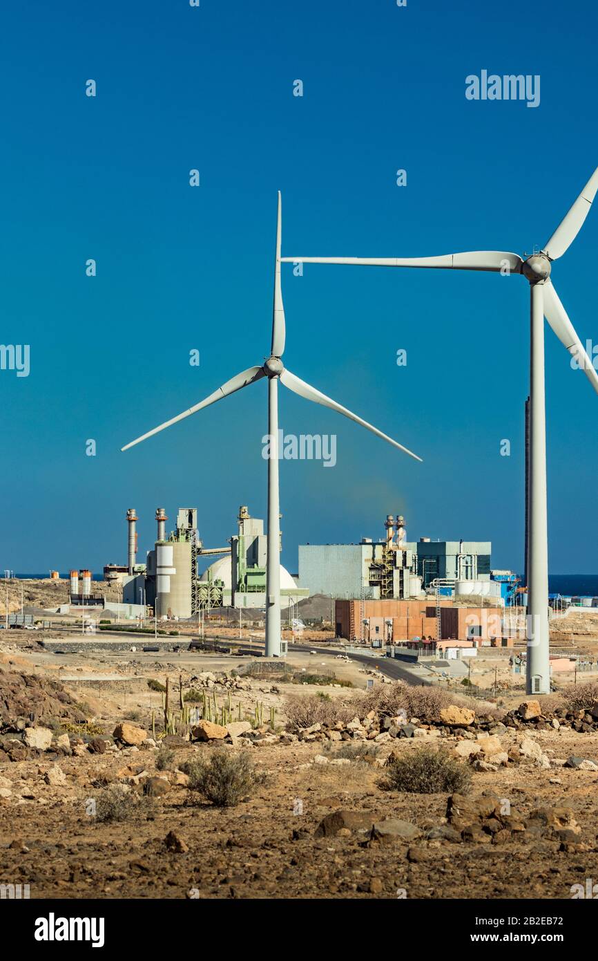 Thermal power station and a series of wind turbines near the sea coast. Wind farm eco field. Eolic park with blue sky in background. Green, ecological Stock Photo