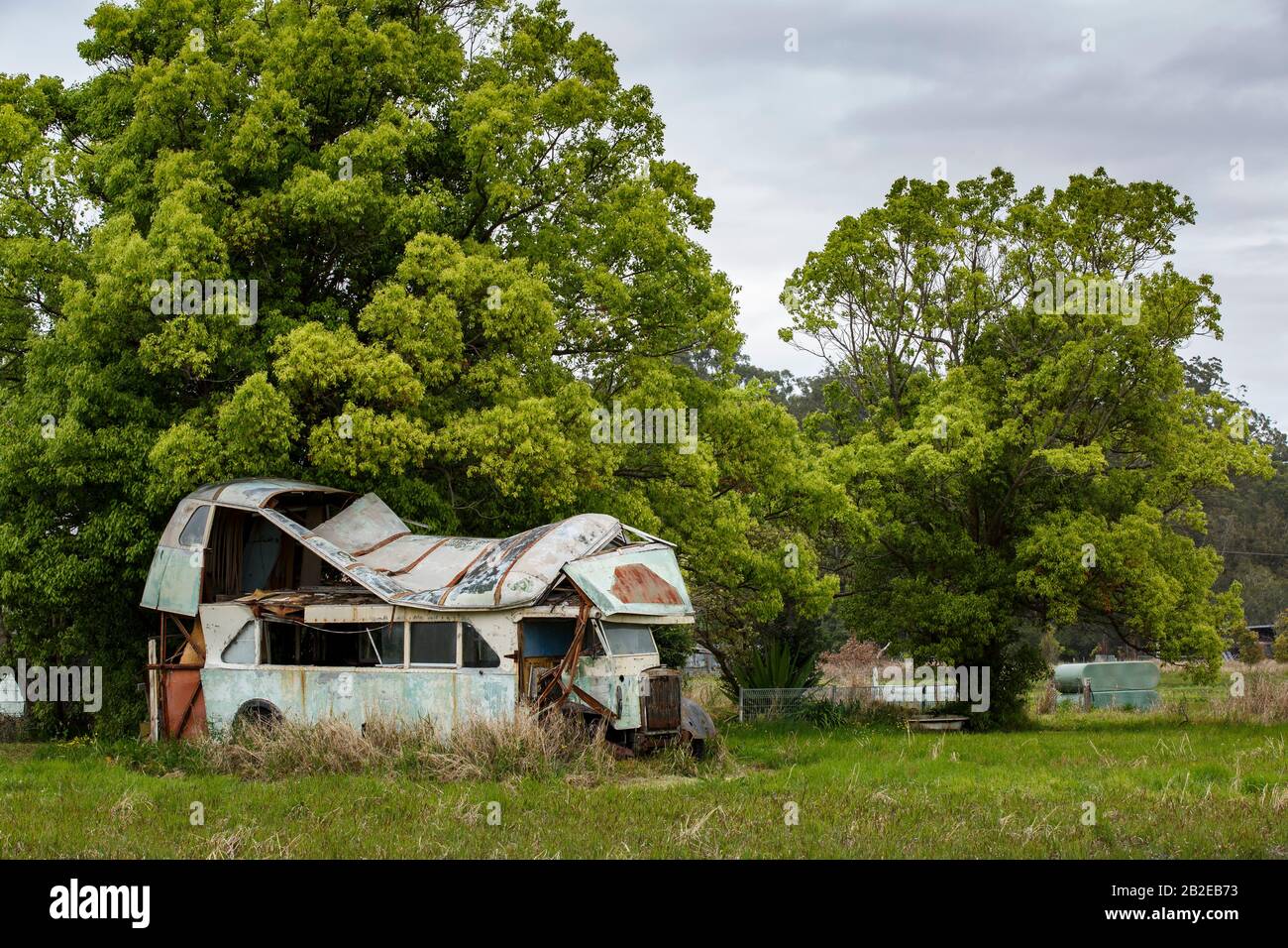 rusted and abandoned bus or truck with severe roof damage Stock Photo