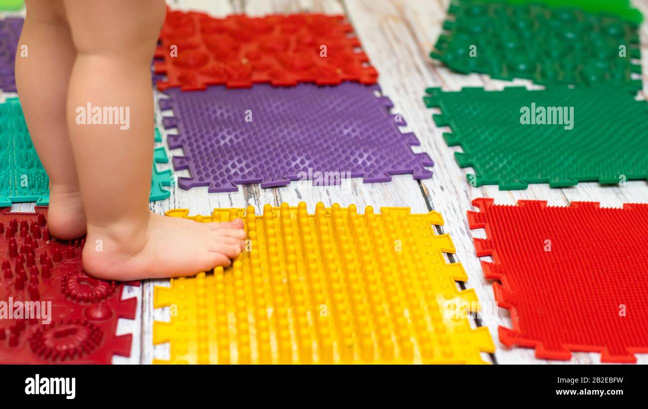 toddler kid feet standing on special massaging and orthopedic mat