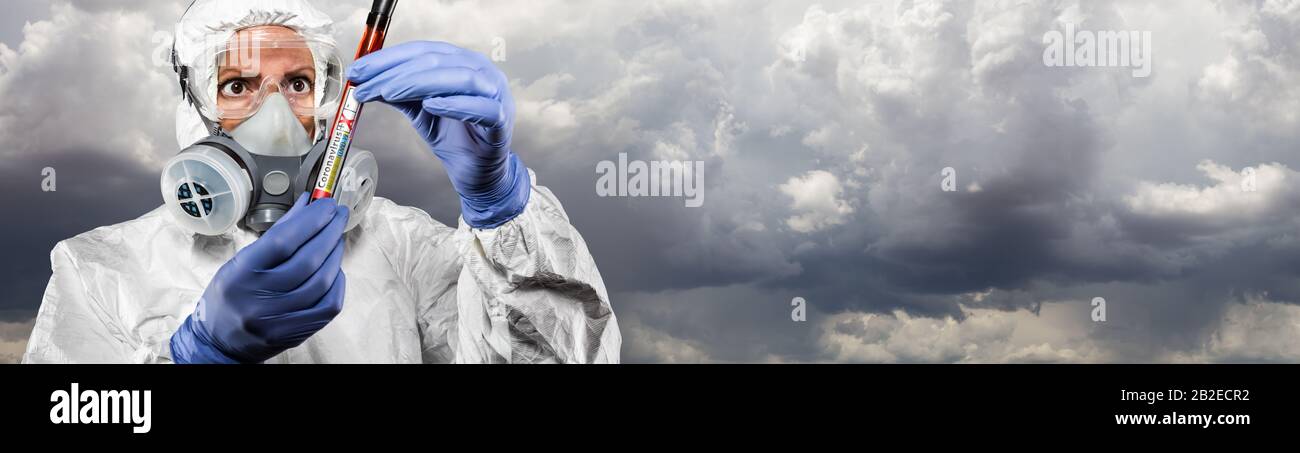 Female Doctor or Nurse In Hazmat Gear Holding Positive Coronavirus Test Tube Cloudy Sky Banner. Stock Photo