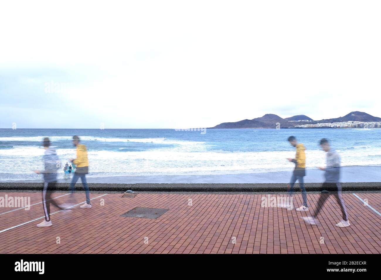 Two young men using smartphones and walking along the sea, double exposure image with intensional motion blur. Stock Photo