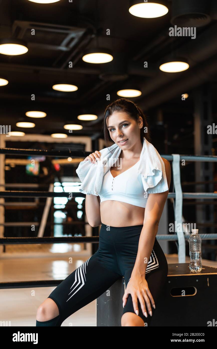Smiling fit girl holding towel and taking rest in gym Stock Photo - Alamy