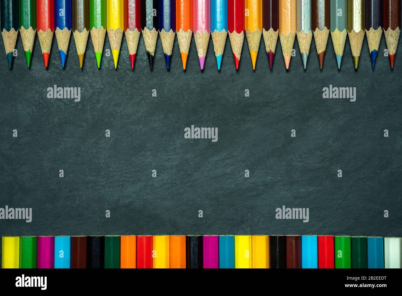 Colored pencils on chalkboard background. Top view and copy space