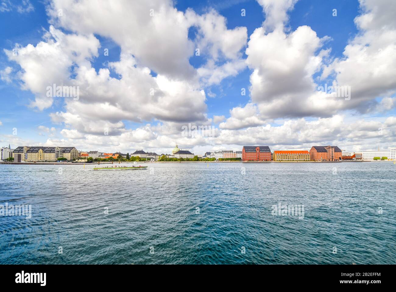 A tourist cruise boat floats past Amalienborg castle and the Marble or Frederik's Church on the water near Holmen Island harbor in Copenhagen Denmark. Stock Photo