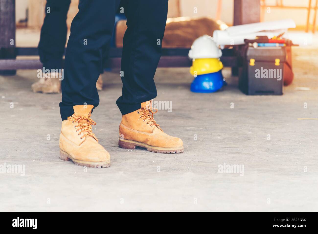 Footwear concept.Handsome man wear jeans knelt down to do up his shoelaces. Preparing before go to party. Brown boots on green grass. close up man han Stock Photo