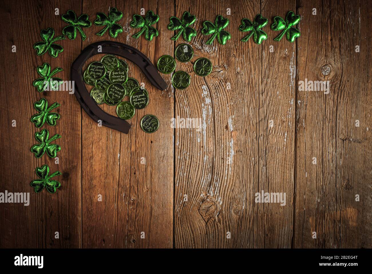Background with rusty horseshoe and clover leaves and coins over rustic wood. St.Patrick's day holiday symbol. Lucky charms. Top view, copy space. Stock Photo
