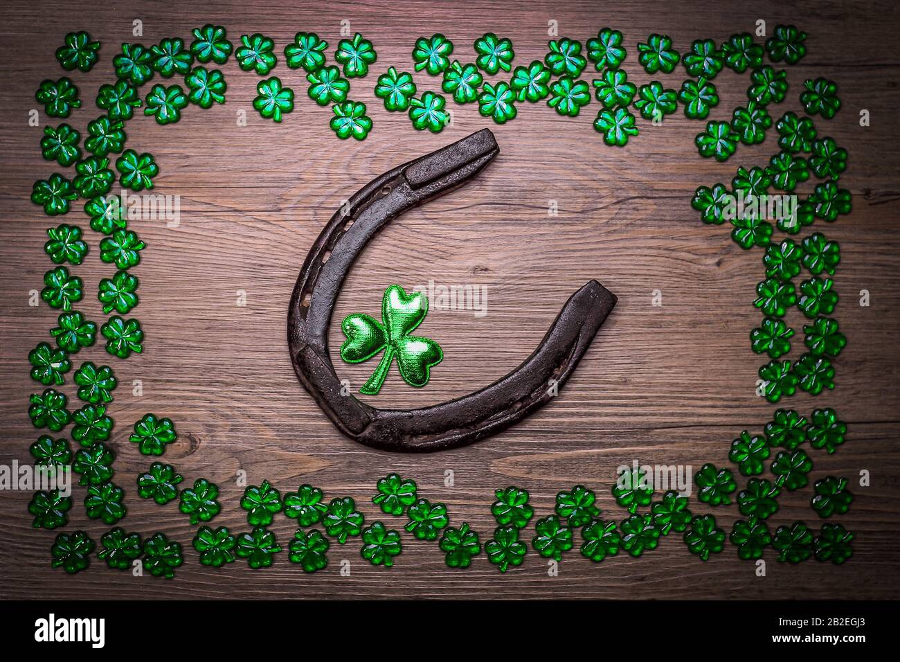 Background with rusty horseshoe, shamrocks over rustic wood. St.Patrick's day holiday symbol. Lucky charms. Top view, copy space. Stock Photo