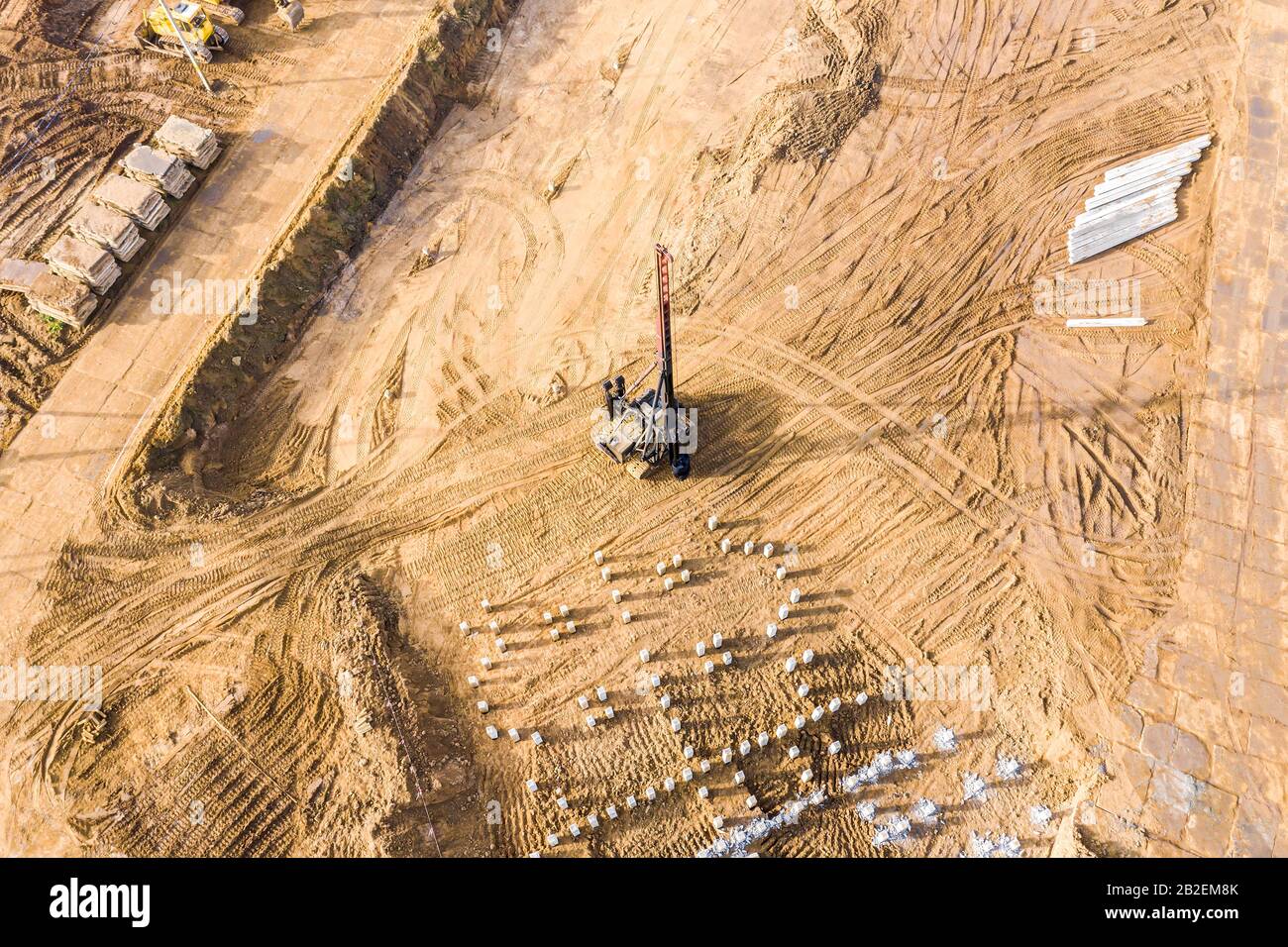 pile driver at work in foundation pit. construction of apartment building. aerial view from flying drone Stock Photo