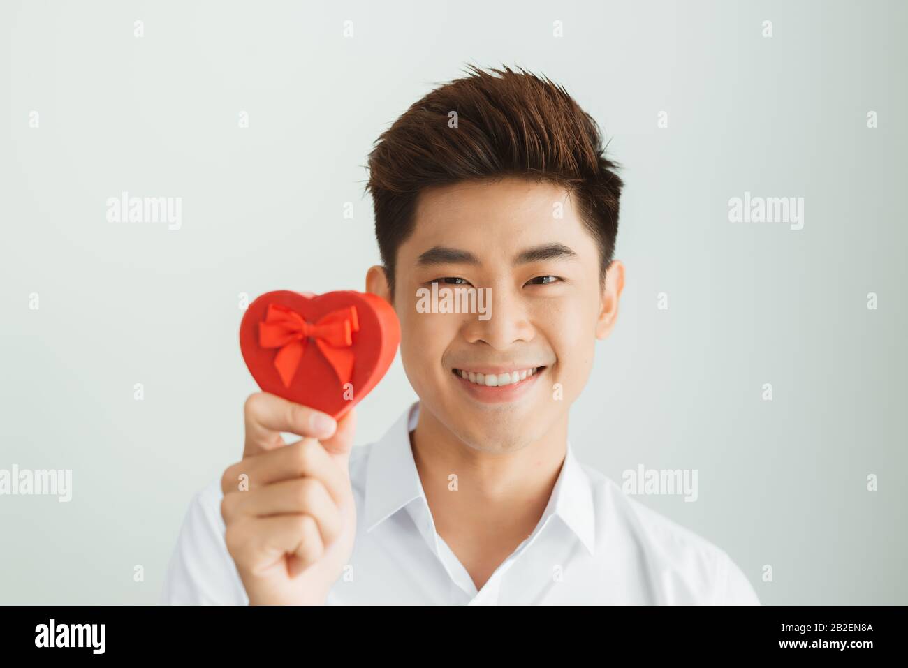 Handsome young man holding red heart box on white background Stock ...