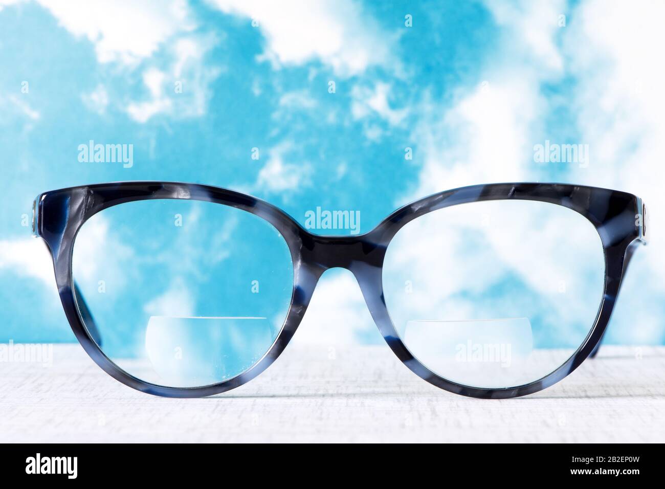 Eyeglasses Glasses with Bifocals and Black Blue Frame smudged agaist a blue and cloudy sky Stock