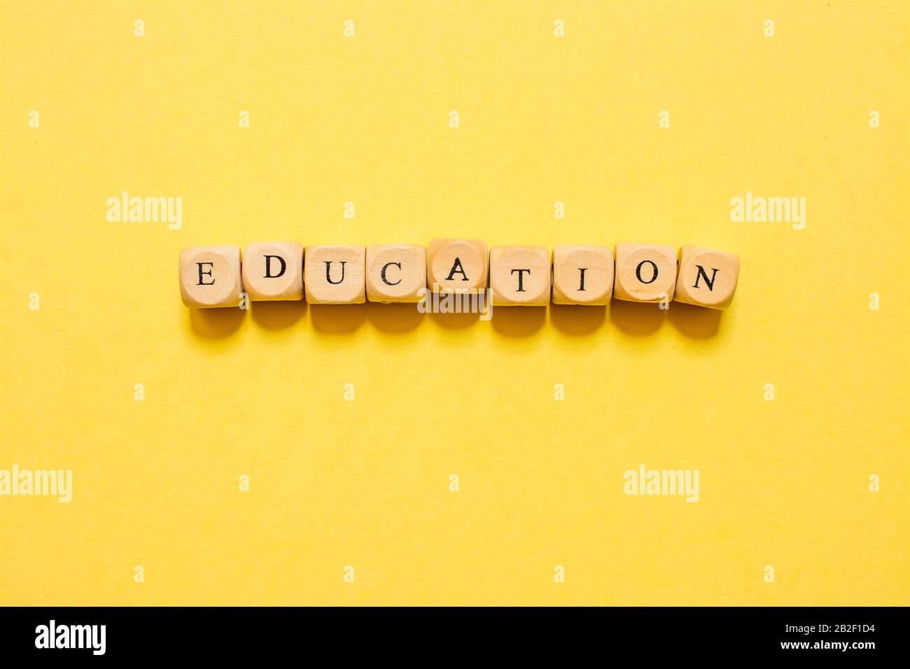 the word Education, text made with dice on yellow background Stock