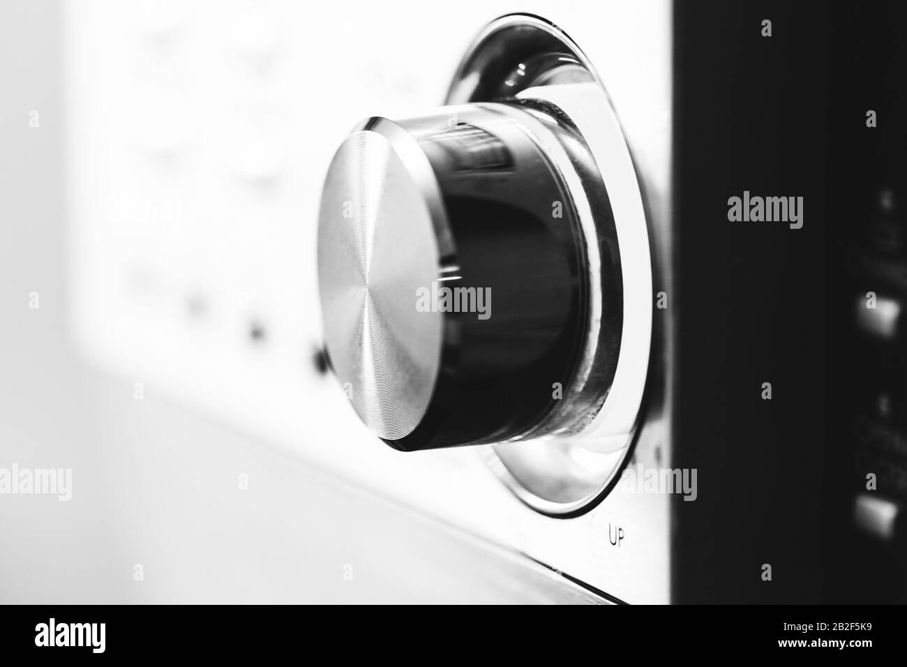 Shiny metallic volume control knob, close up black and white photo with selective soft focus Stock Photo