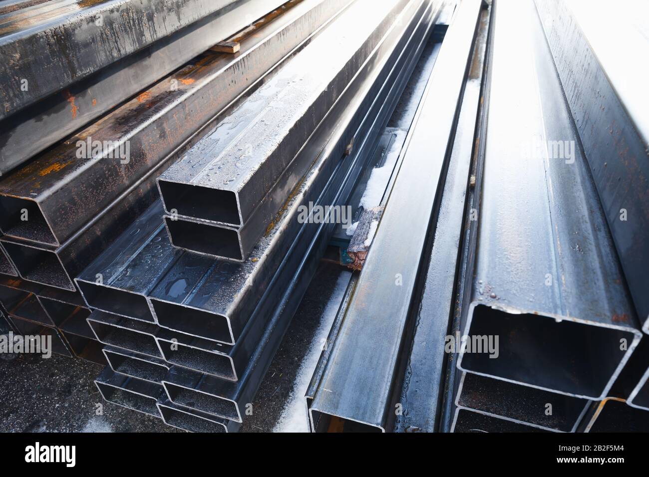 Stack of rolled metal products is in a storage, perspective view of steel pipes of rectangular cross-section Stock Photo