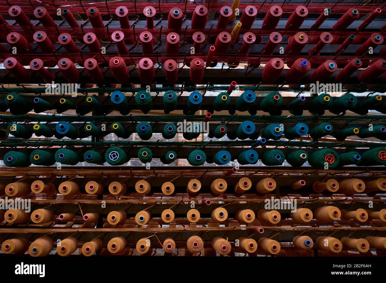 Rows of thread on spools are ready to supply a weaving loom. At the
