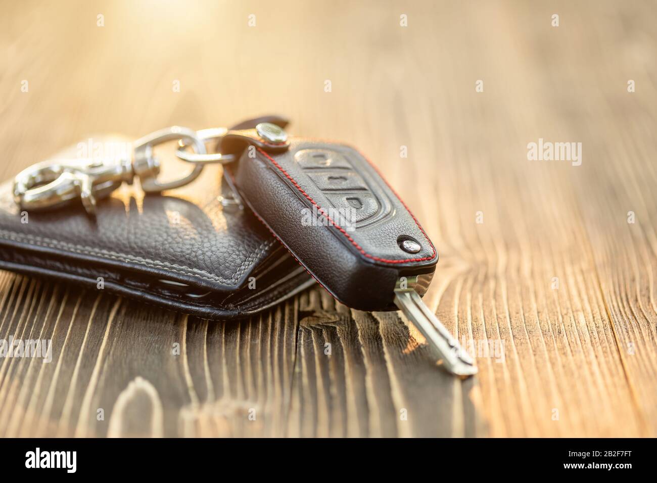 Close up new car keys with black leather wallet on wooden table. Car purchase or car rental concept Stock Photo