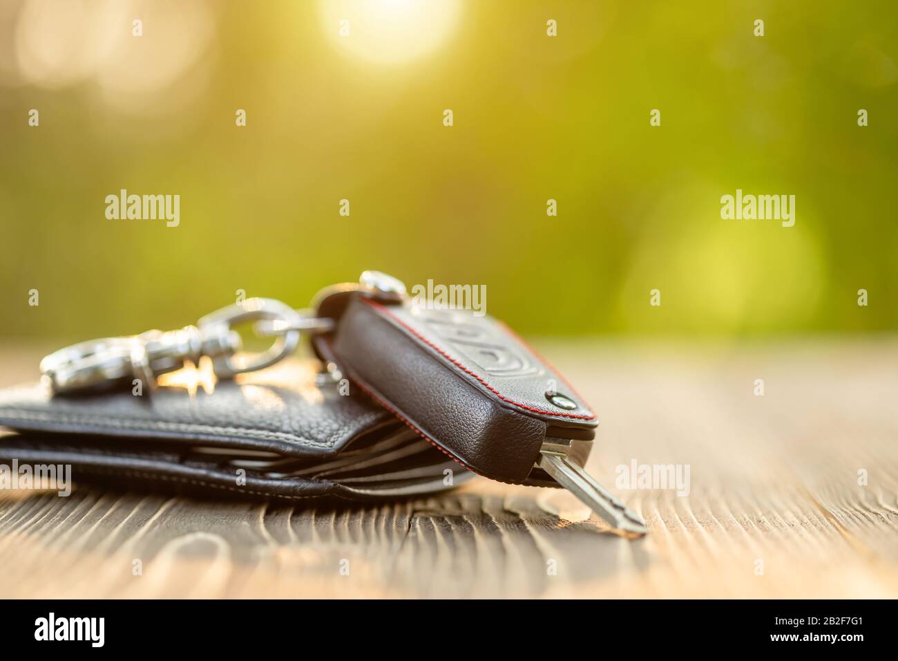 Close up new car keys with black leather wallet on wooden table. Car purchase or car rental concept Stock Photo