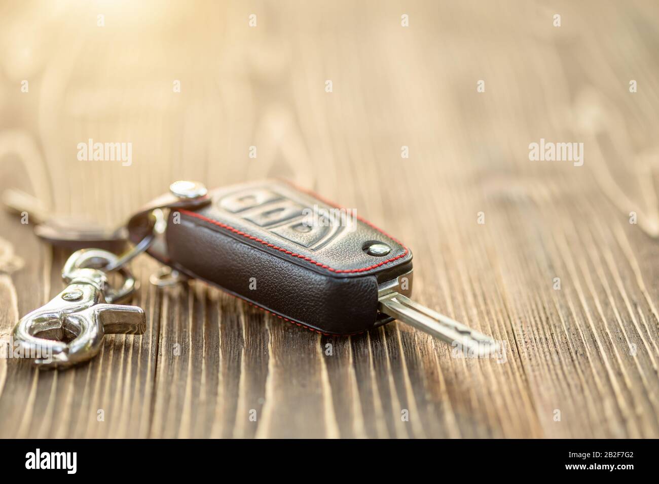 Close up new car keys with black leather cover on wooden table Stock Photo