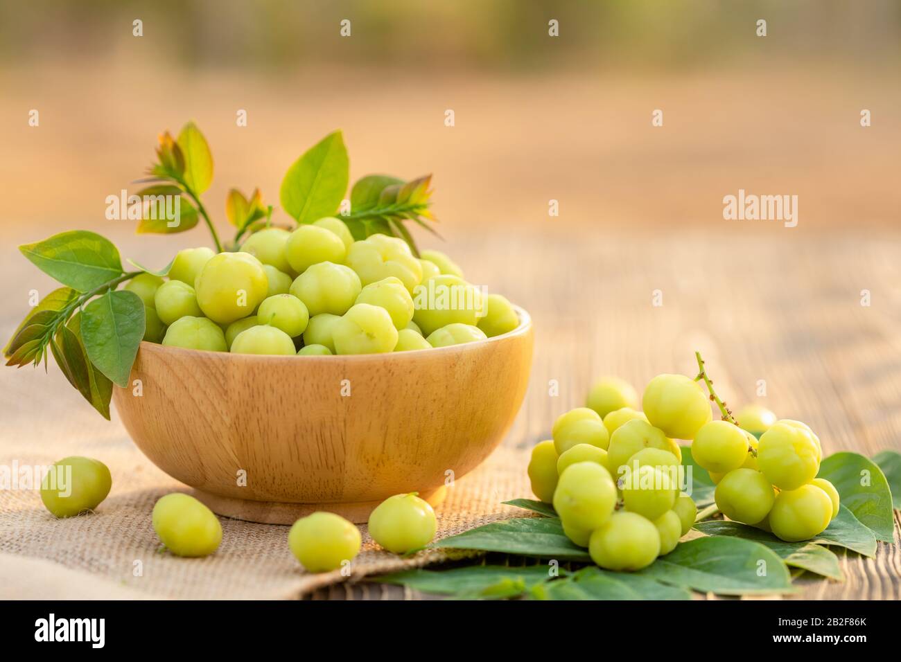 Close up fresh green star gooseberry (tropical Thai fruit) in bowl on wooden plank background Stock Photo
