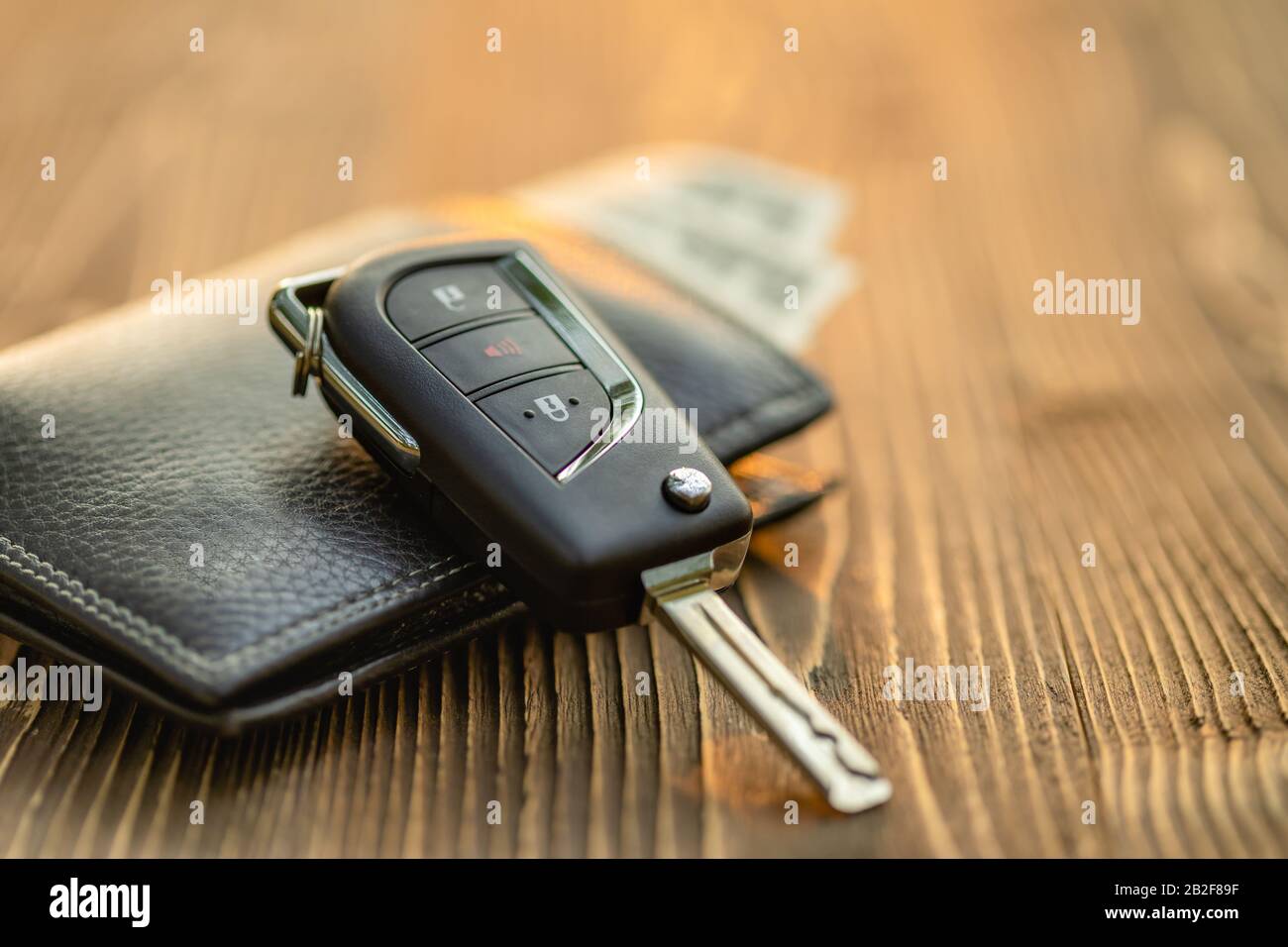 Close up new car keys with US dollar banknote on wooden table. Car purchase or car rental concept Stock Photo