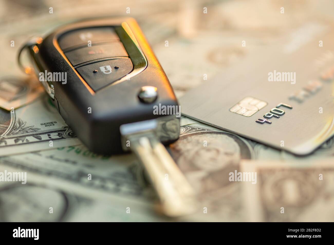 Close up new car keys, credit card and US dollar banknote on wooden table. Car purchase or car rental concept Stock Photo