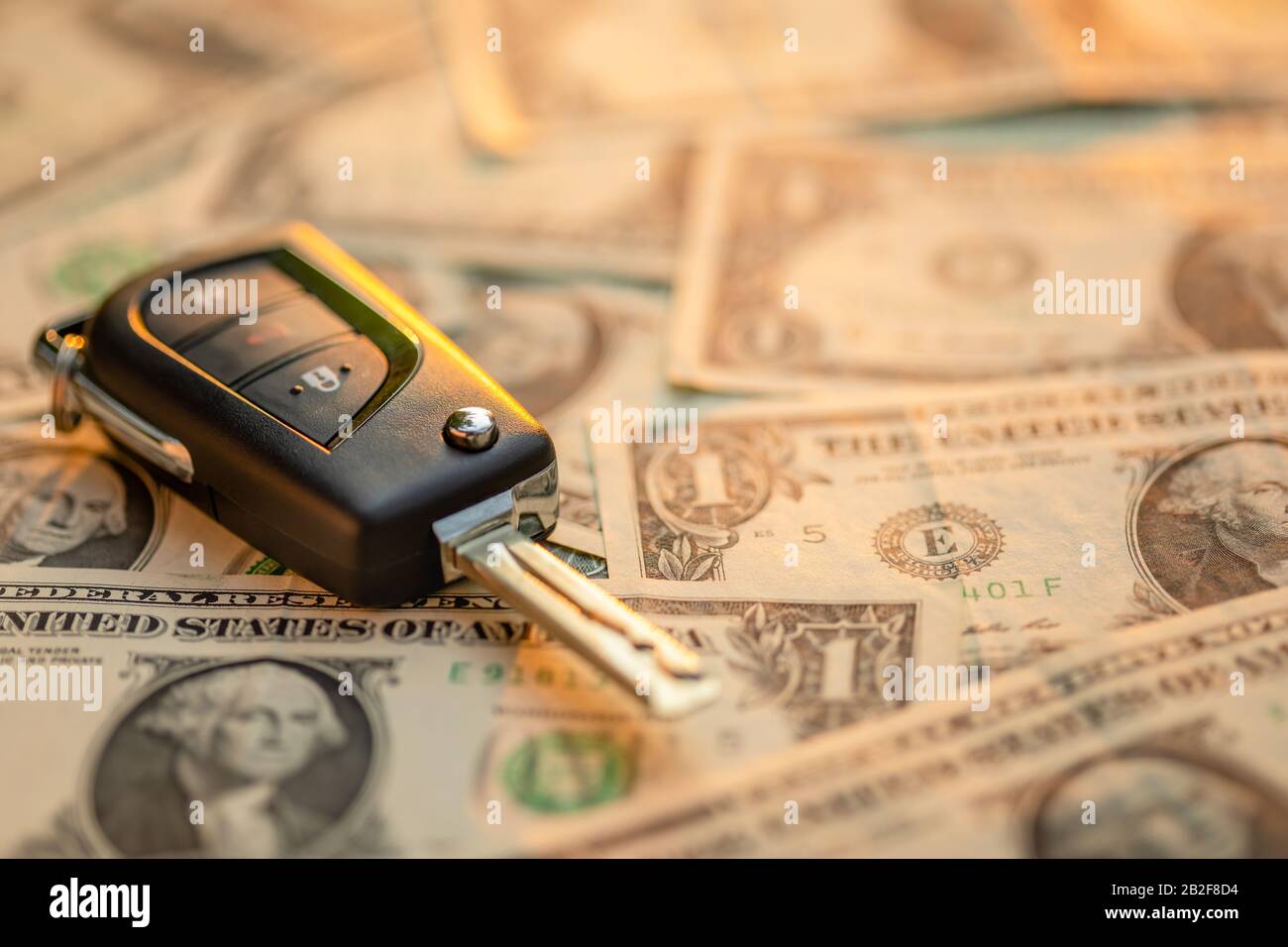 Close up new car keys with US dollar banknote on wooden table. Car purchase or car rental concept Stock Photo